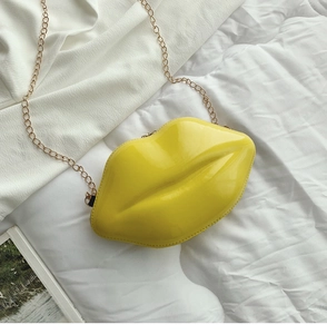 Macro detail of yellow lip-shaped crossbody bag featuring glossy patent leather and gold chain