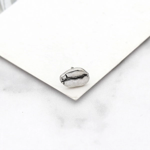 Gros plan sur boucle d'oreille grain de café argentée avec texture vintage