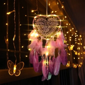 Pink heart dreamcatcher with warm LED lights and feathers in a cozy setting