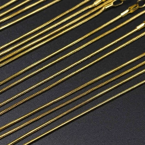 Golden snake bone chains for DIY jewelry making displayed on a black background