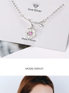 Macro detail of cherry blossom necklace with pink gemstone and silver branch design