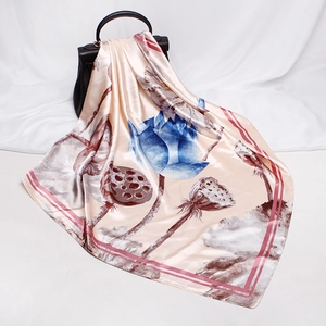 Detail of silk square scarf with blue lotus prints draped over a black handbag
