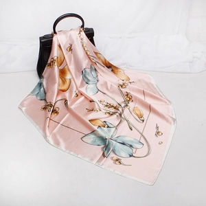Close-up of pink floral silk scarf with colorful botanical patterns on a black handbag