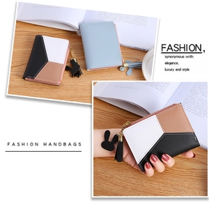 Detailed view of compact zip wallet with stitching and rabbit tassel accessory