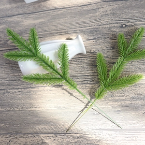 Artificial green pine needles stems for DIY Christmas crafts and home decor on wood background