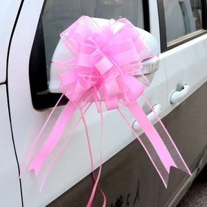 Pink ribbon bow made of organza and silk attached to a white car mirror for decoration