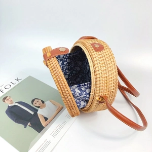 Detail of round woven rattan bag showing floral lining and brown leather strap