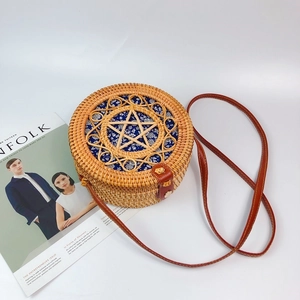 Detail of round handmade rattan bag with blue floral fabric and leather strap