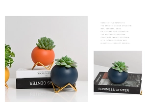 Close-up of Morandi ceramic spherical pots with minimalist golden triangle metal stands
