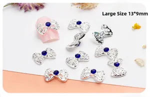 Macro detail of 13x9mm silver hollow bow nail charm with a blue rhinestone inlay