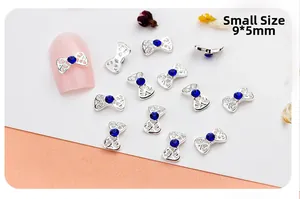 Detail view of 9x5mm hollow silver bow nail charm with blue rhinestones on pink nail