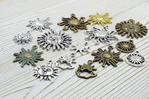 Mix of antique silver and bronze sun pendants for DIY jewelry making on wood background