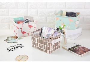 Close-up of small printed canvas storage baskets with handles on a white desktop