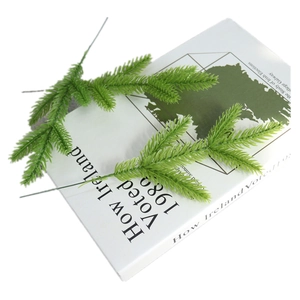 Artificial green pine needles on white book for Christmas DIY decor and floral arrangements