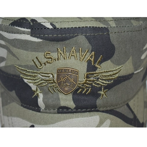Detalle del bordado US NAVAL y emblema metálico en la gorra militar con diseño de camuflaje