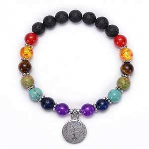 Close-up of lava stone chakra bracelet with silver Tree of Life charm on white background