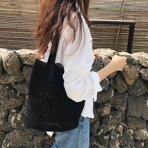 Detail of black crochet tote bag featuring geometric knit texture and leather strap