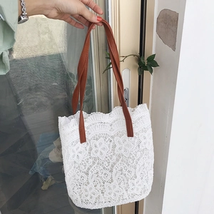 Detailed close-up of floral lace bucket bag with brown faux leather handles
