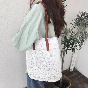 Close-up of white floral lace tote bag with brown leather strap worn by a model