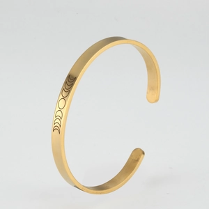 Detail view of gold open bangle featuring precision engraved moon phase patterns