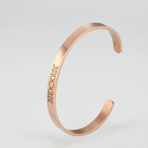 Detail of rose gold open cuff bracelet featuring minimalist moon phase engravings