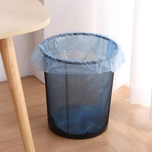 Modern black metal mesh waste bin with blue liner on a natural wooden floor