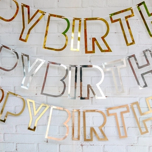 Three metallic Happy Birthday banners in gold, silver and rose gold on a white wall