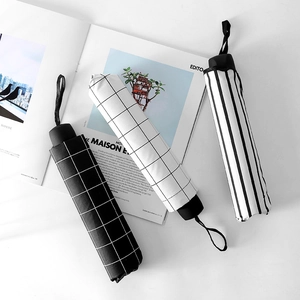 Three minimalist black and white striped and checkered folding umbrellas on a magazine