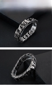 Detailed view of punk skull charm and scale-textured stainless steel links on men's bracelet