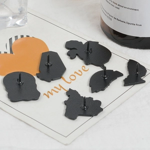Detailed back view of six black alloy pins with sharp needles on decorative card paper