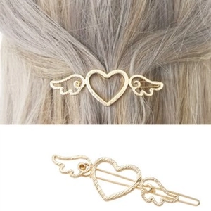 Close-up of golden hollow heart wings hair clip with matte texture on blonde hair