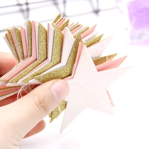 Detail of glitter gold and pink paper star garlands for birthday party decorations
