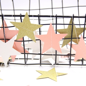 Pink white and gold glitter star garlands draped on a black wire basket for party decor