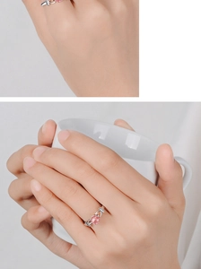 Detailed close-up of a silver strawberry quartz planet ring on a finger by a white mug