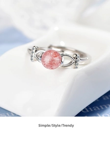 Macro shot of natural pink strawberry quartz ring with zircons on white ceramic stand