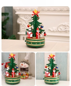 Detailed view of a green wooden Christmas tree music box with miniature figurines