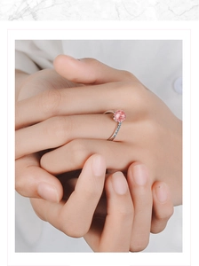 Close-up of model wearing a silver ring with a round pink stone on marble background