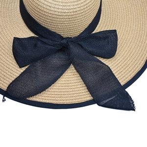 Detail of wide brim straw hat featuring textured weave and large black mesh bow
