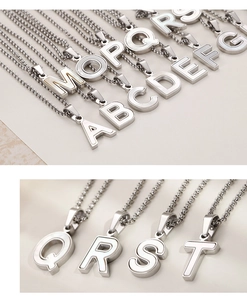 Détail macro du collier pendentif alphabet en acier argenté avec incrustation de nacre
