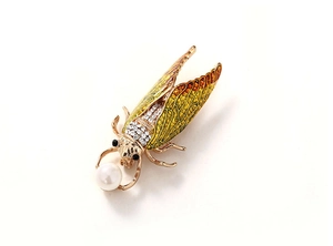 Close-up of golden cicada brooch with enamel wings, rhinestones and a large pearl