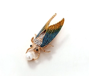 Detail of golden cicada brooch with blue enamel wings, rhinestones, and white pearl