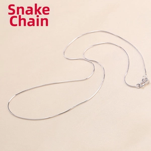 Detail view of a slim 925 sterling silver snake chain necklace on beige fabric