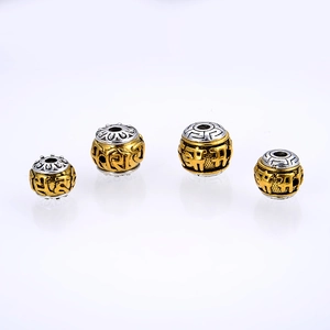 Detailed macro of two-tone alloy beads with embossed Sanskrit mantras and lotus patterns