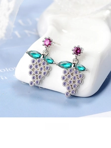 Macro detail of grape-shaped earrings with purple crystals and green gemstone leaves