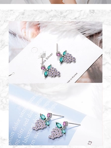 Detail view of grape-shaped earrings with purple and green zircon stones on silver base