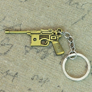 Detailed close-up of a bronze metal miniature pistol keychain with antique finish details