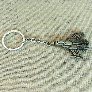 Detail shot of a bronze jet fighter airplane keychain with vintage textured metal finish
