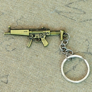 Macro detail of a bronze-colored metal MP5 submachine gun replica keychain on burlap