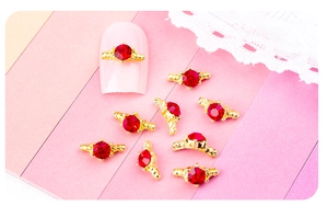 Vue détaillée du bijou d'ongle en forme de couronne avec strass rouge sur rose