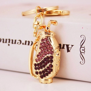 Golden golf bag keychain with purple rhinestones on white book background